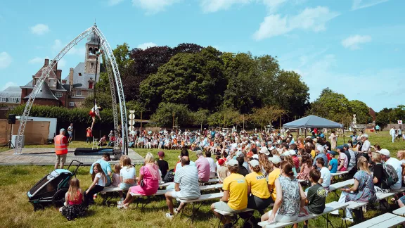 een grasveld waar mensen naar een optreden van een acrobaat zitten te kijken