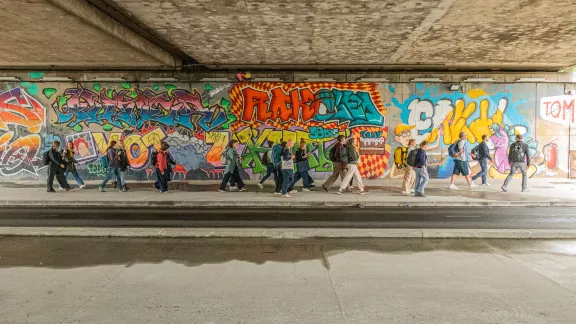 groep mensen die langs een graffitimuur lopen