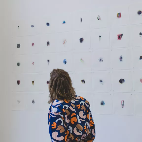 Vrouw die naar een kunstinstallatie aan de muur aan het kijken is